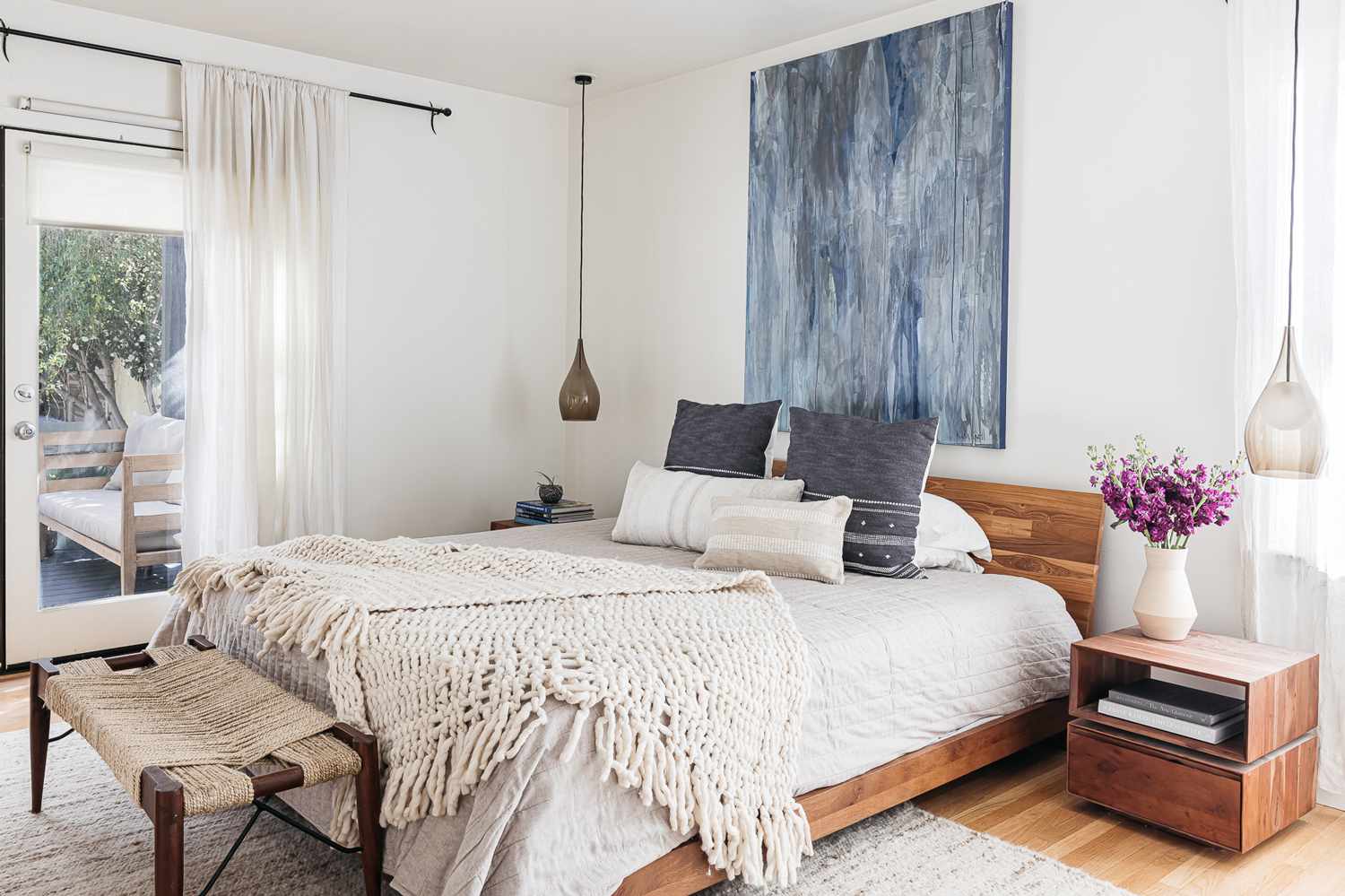 Warm bedroom with layered linens, a curved headboard, and soft natural light